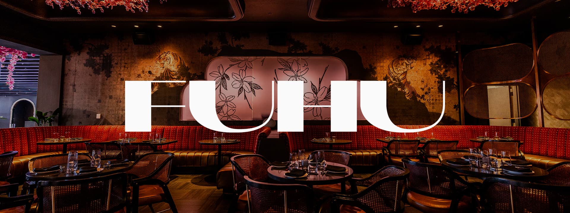 Banner featuring the interior of FUHU restaurant with modern dining tables, red banquette seating, floral ceiling décor, tiger wall murals, and the FUHU logo displayed prominently across the center.